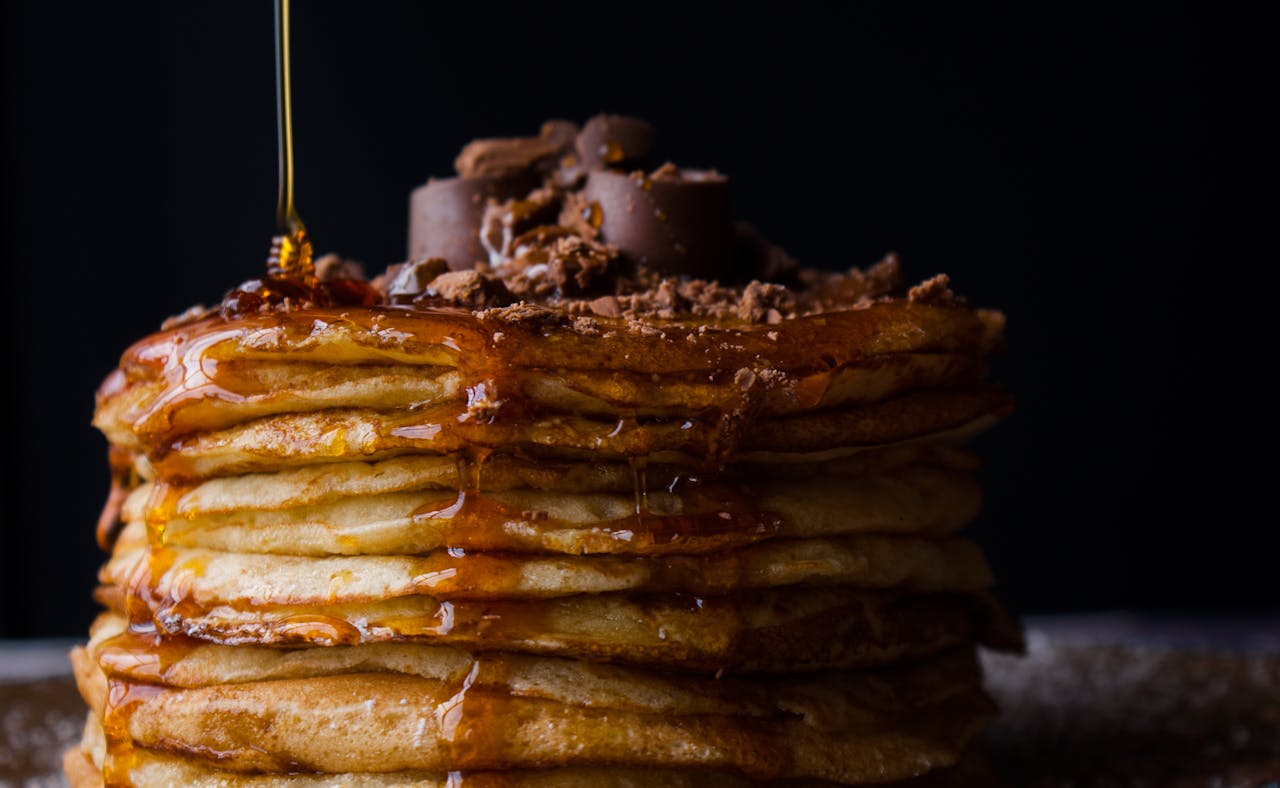 who-we-are Mouthwatering stack of pancakes topped with chocolate and syrup. Perfect breakfast delight.